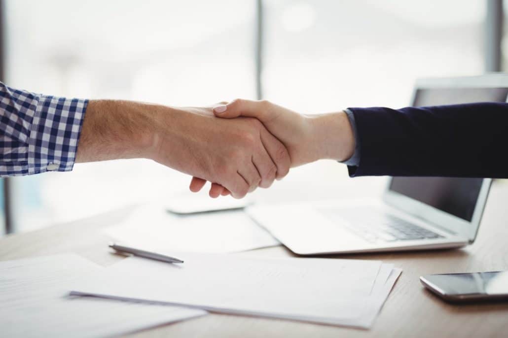 Close-up of executives shaking hands at desk